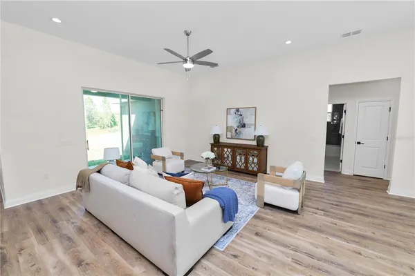 a living room with furniture kitchen view and a wooden floor