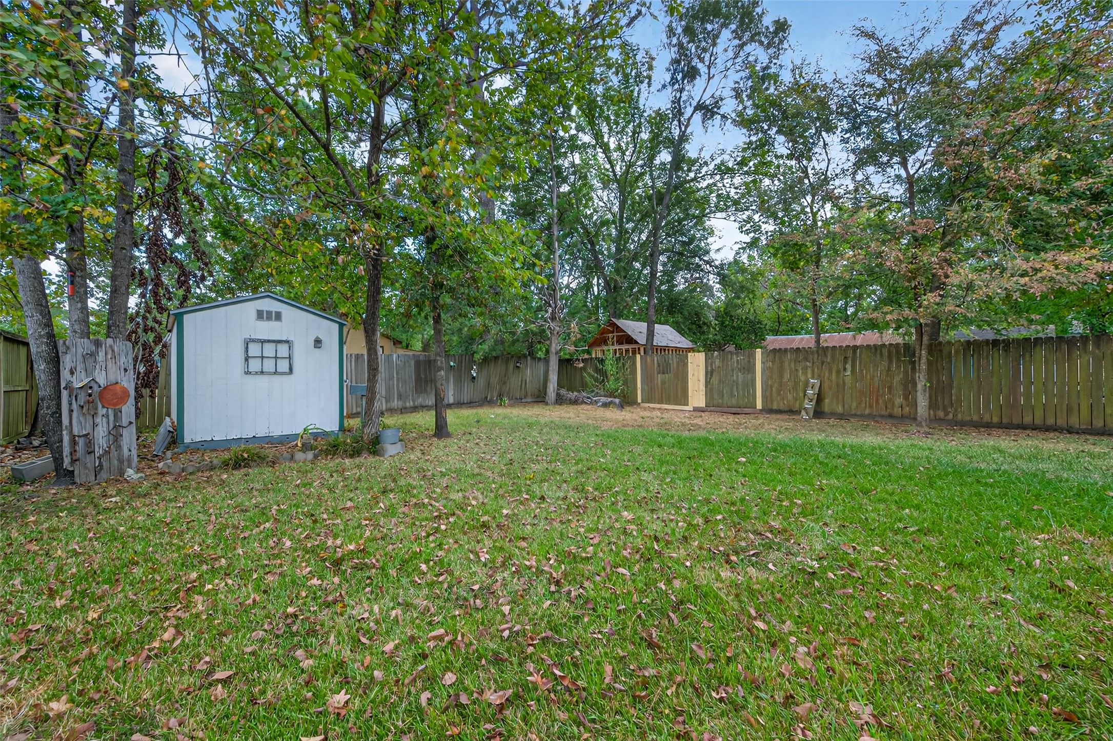 1020 Houston Street Conroe, TX 77301 - Photo 41 of 43 a backyard of a house with large trees and wooden fence
