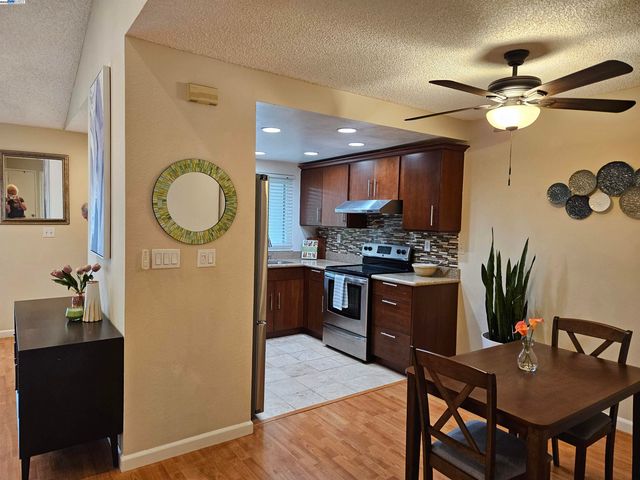 a kitchen with a refrigerator a stove cabinets dining table and chairs