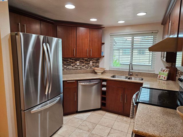 a kitchen with stainless steel appliances granite countertop a refrigerator a sink a stove and a refrigerator