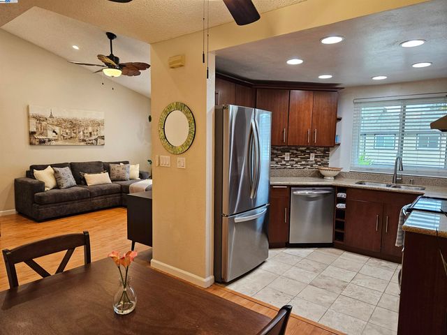 a kitchen with stainless steel appliances granite countertop a refrigerator a sink a stove and island