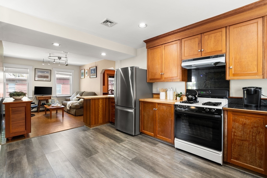 52 Lewis Avenue Arlington, MA 02474 - Photo 10 of 40 a kitchen with stainless steel appliances granite countertop a stove top oven a refrigerator a sink dishwasher a dining table and chairs with wooden floor
