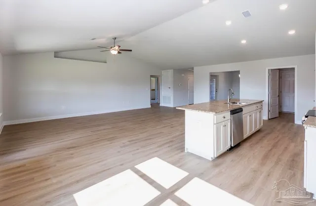 a view of a kitchen with a sink and dishwasher with wooden floor