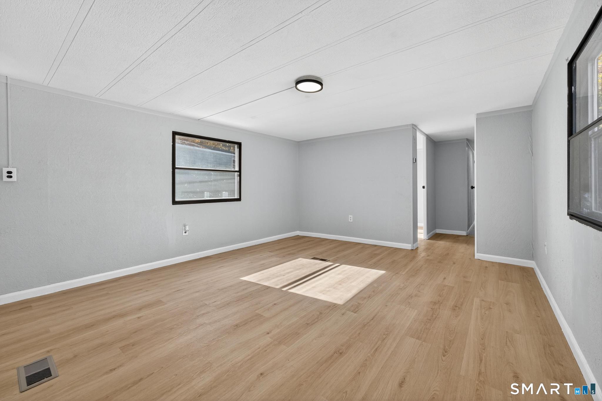 32 Nashua Street Norwich, CT 06360 - Photo 9 of 19 an empty room with wooden floor and windows