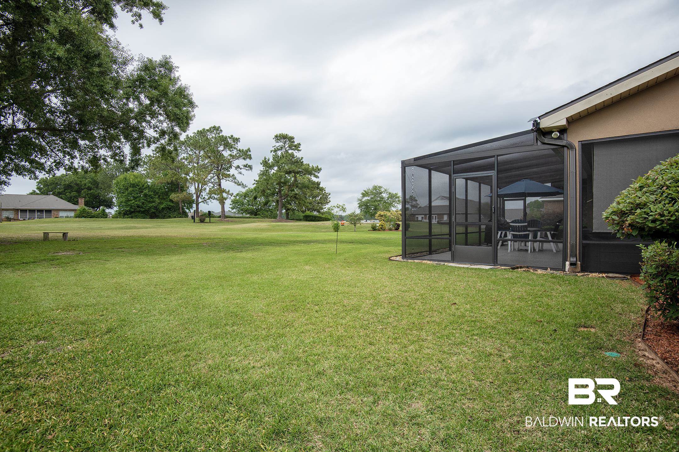 9357 Lakeview Drive Foley, AL 36535 - Photo 13 of 68 Expansive green lawn featuring a screened patio structure with a dark frame, providing outdoor living space