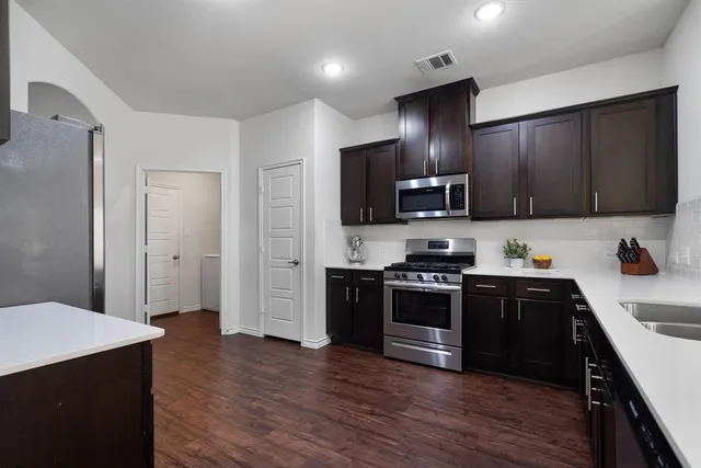 a kitchen with stainless steel appliances granite countertop wooden cabinets a stove a sink and a refrigerator