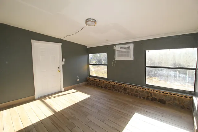 a view of empty room with a window and wooden floor