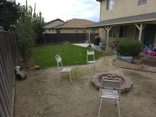 a view of a backyard with table and chairs with a fire pit and potted plants