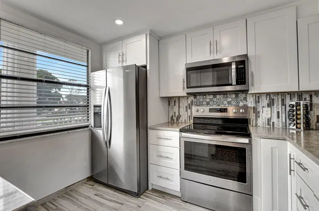 a kitchen with cabinets stainless steel appliances and a window