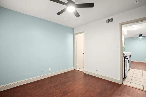 an empty room with wooden floor and chandelier fan
