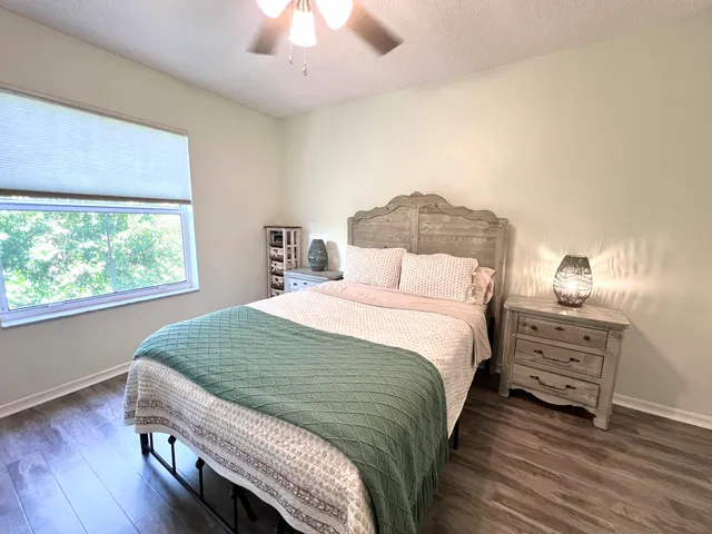 a bedroom with a bed a chandelier and next to a window