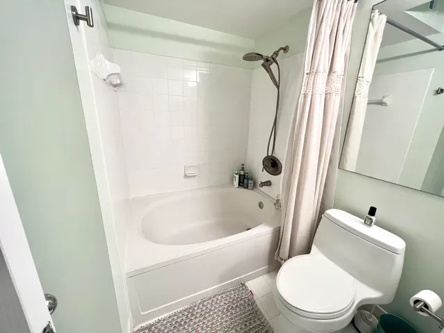 a white toilet sitting next to a bath tub