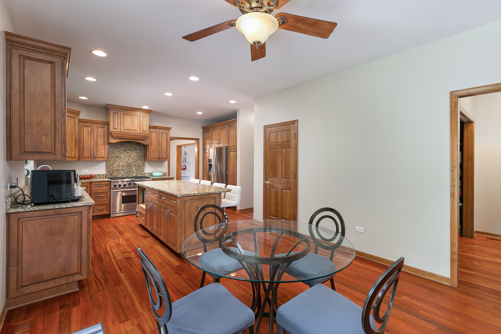 23W250 Hampton Circle Naperville, IL 60540 - Photo 18 of 42 a open kitchen with stainless steel appliances granite countertop a stove a refrigerator a sink a dining table and chairs with wooden floor