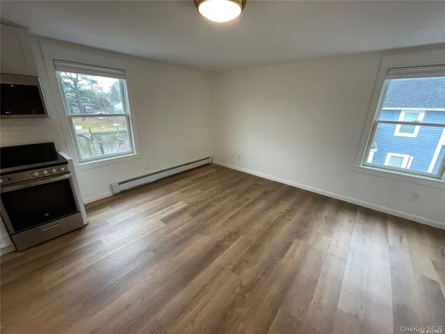 an empty room with wooden floor cabinet and windows