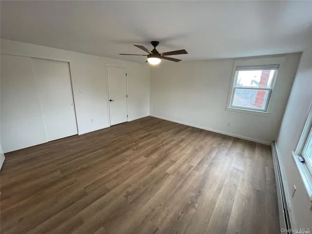 an empty room with wooden floor fan and windows