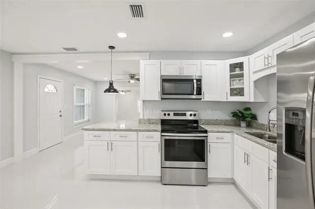 a kitchen with granite countertop a sink stainless steel appliances and white cabinets