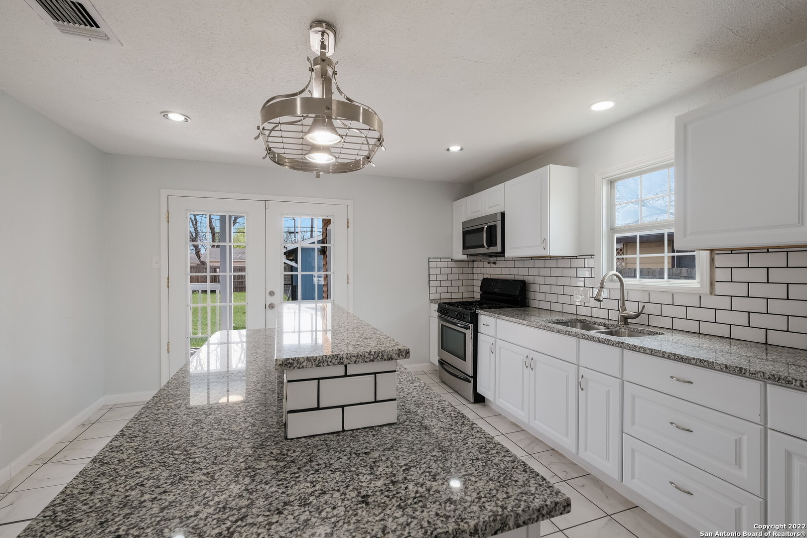 a large kitchen with stainless steel appliances granite countertop a sink stove and cabinets