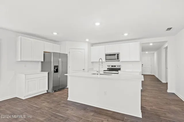 a kitchen with stainless steel appliances a refrigerator sink and white cabinets