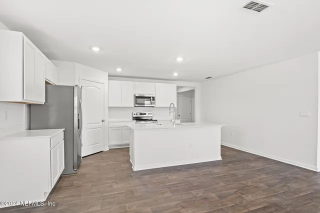 a view of kitchen with stainless steel appliances refrigerator stove microwave and cabinets
