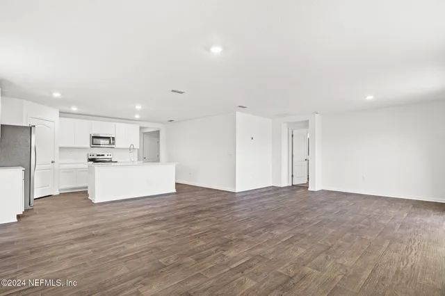 a view of kitchen with granite countertop cabinets and refrigerator