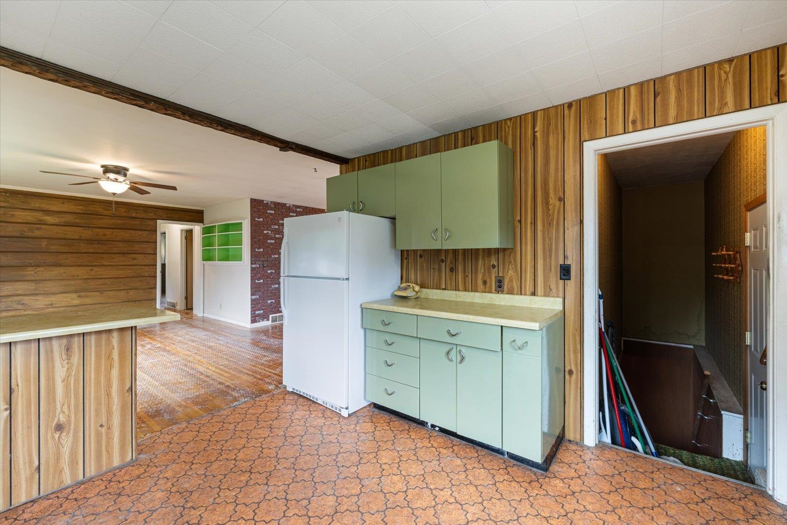 202 Suffolk Drive Hoyt Lakes, MN 55750 - Photo 13 of 33 Kitchen with green cabinetry, wood walls, freestanding refrigerator, light countertops, and beamed ceiling