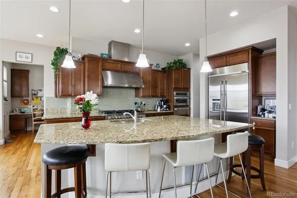 a kitchen with kitchen island granite countertop a table chairs sink and cabinets