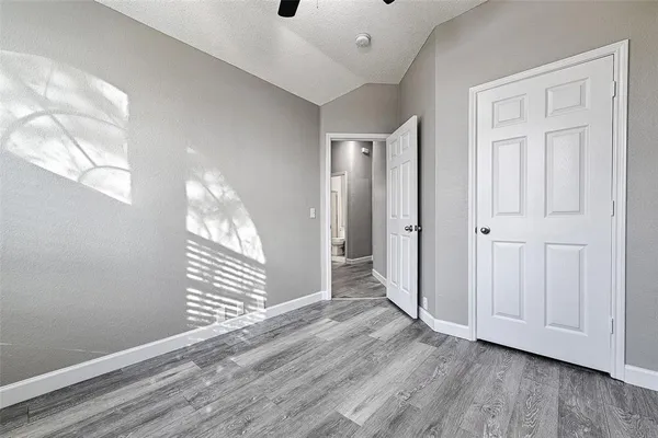 a view of empty room with wooden floor and fan