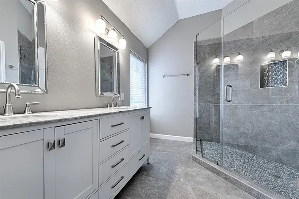 a bathroom with a double vanity sink mirror and shower