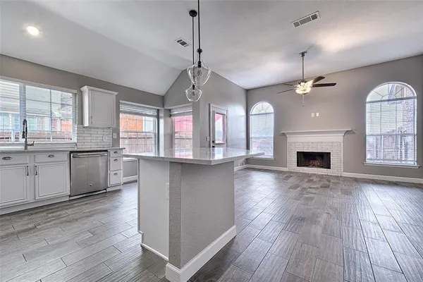 a open kitchen with dishwasher a stove a refrigerator and a fireplace with wooden floor