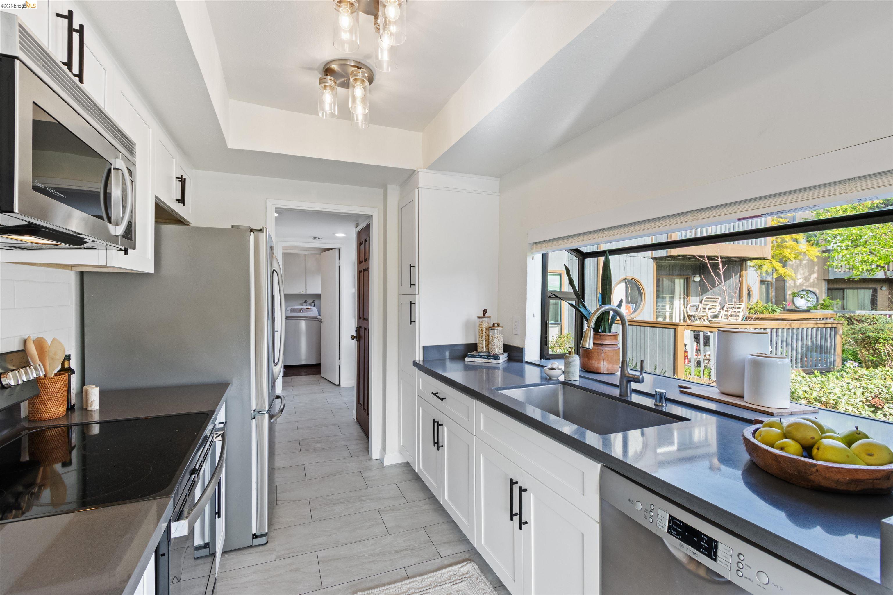 548 Queen's Road Alameda, CA 94501 - Photo 12 of 42 Kitchen with stainless steel appliances, white cabinetry, a tray ceiling, and dark stone counters
