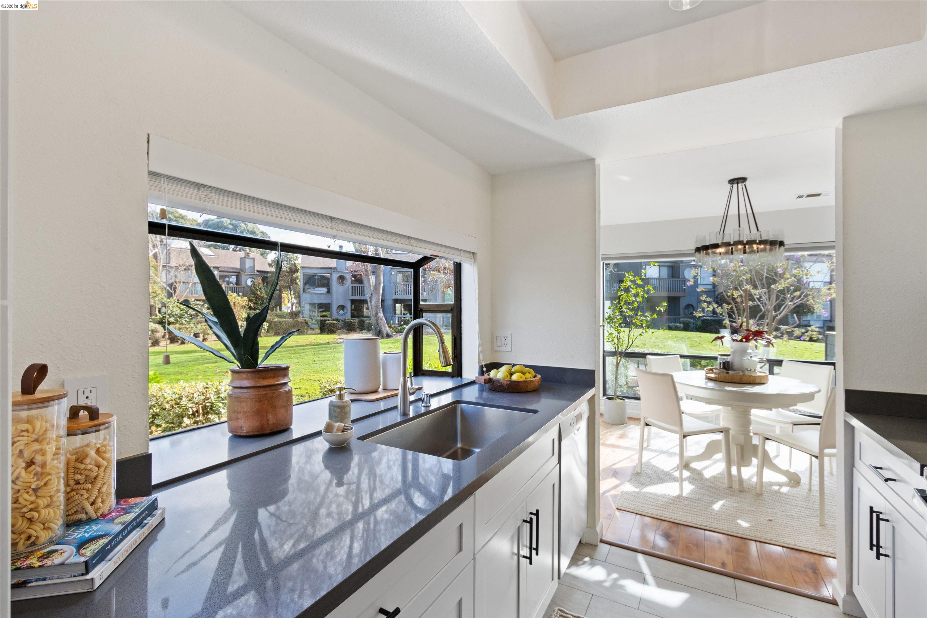 548 Queen's Road Alameda, CA 94501 - Photo 9 of 42 Kitchen with white cabinetry, dishwashing machine, light tile patterned floors, dark stone countertops, and a chandelier