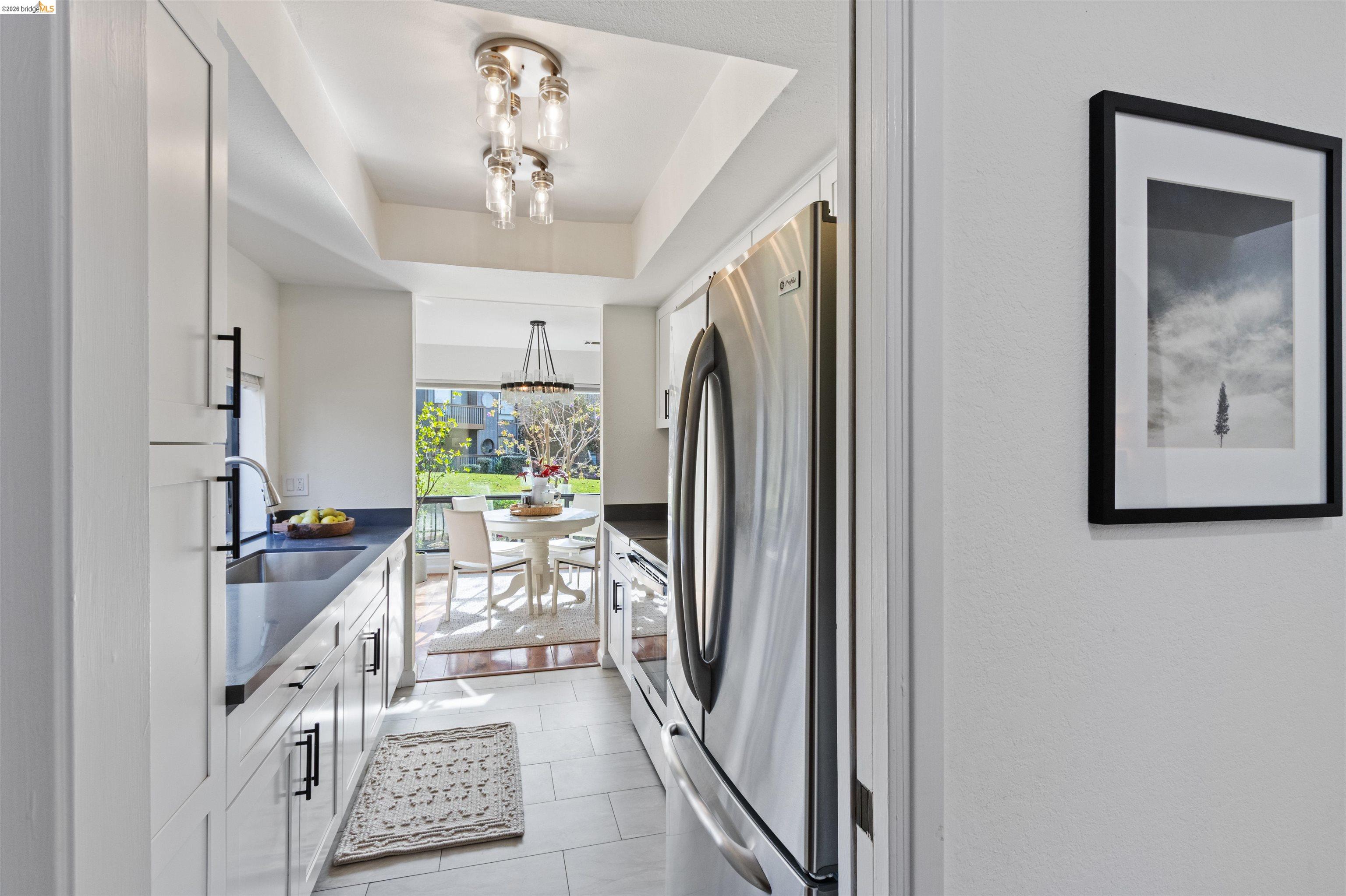 548 Queen's Road Alameda, CA 94501 - Photo 10 of 42 Kitchen with stainless steel appliances, white cabinetry, a tray ceiling, light tile patterned flooring, and suspended lighting