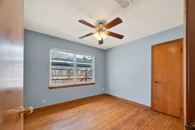 a view of an empty room with window and wooden floor