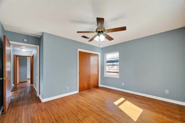 a view of an empty room with window and wooden floor
