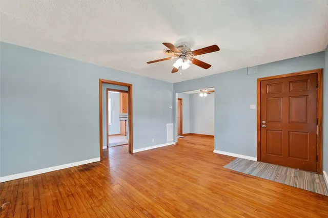 a view of empty room with wooden floor and ceiling fan