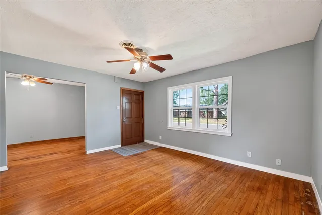 a view of an empty room with a window and wooden floor