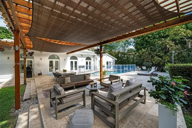 a roof deck with couches and wooden fence with potted plants