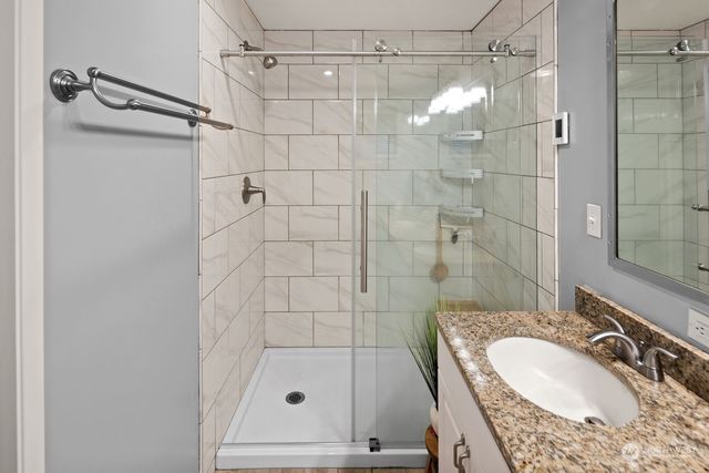 a bathroom with a granite countertop shower a sink and vanity