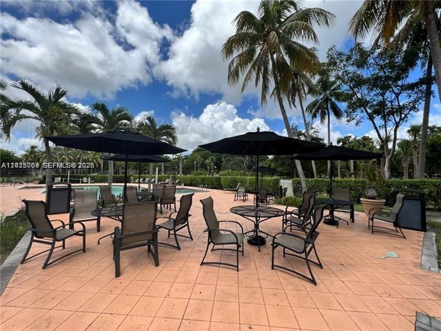 951 Lyons Road, Unit 6206 Coconut Creek, FL 33063 - Photo 12 of 27 a view of a patio with a table and chairs under an umbrella with a barbeque