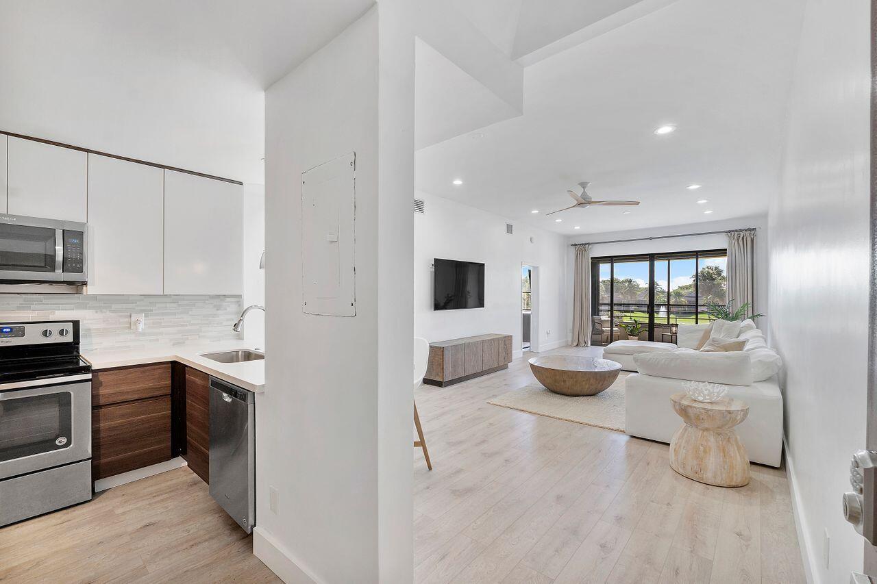 7508 La Paz Boulevard, Unit 304 Boca Raton, FL 33433 - Photo 12 of 44 a kitchen with stainless steel appliances kitchen island granite countertop a sink and dishwasher a stove top oven with wooden floor