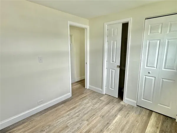 an empty room with wooden floor and a bathroom