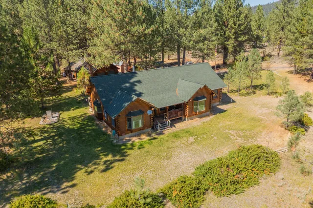 an aerial view of a house with swimming pool and large trees