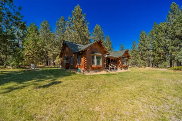 a view of a house with a big yard potted plants and large tree