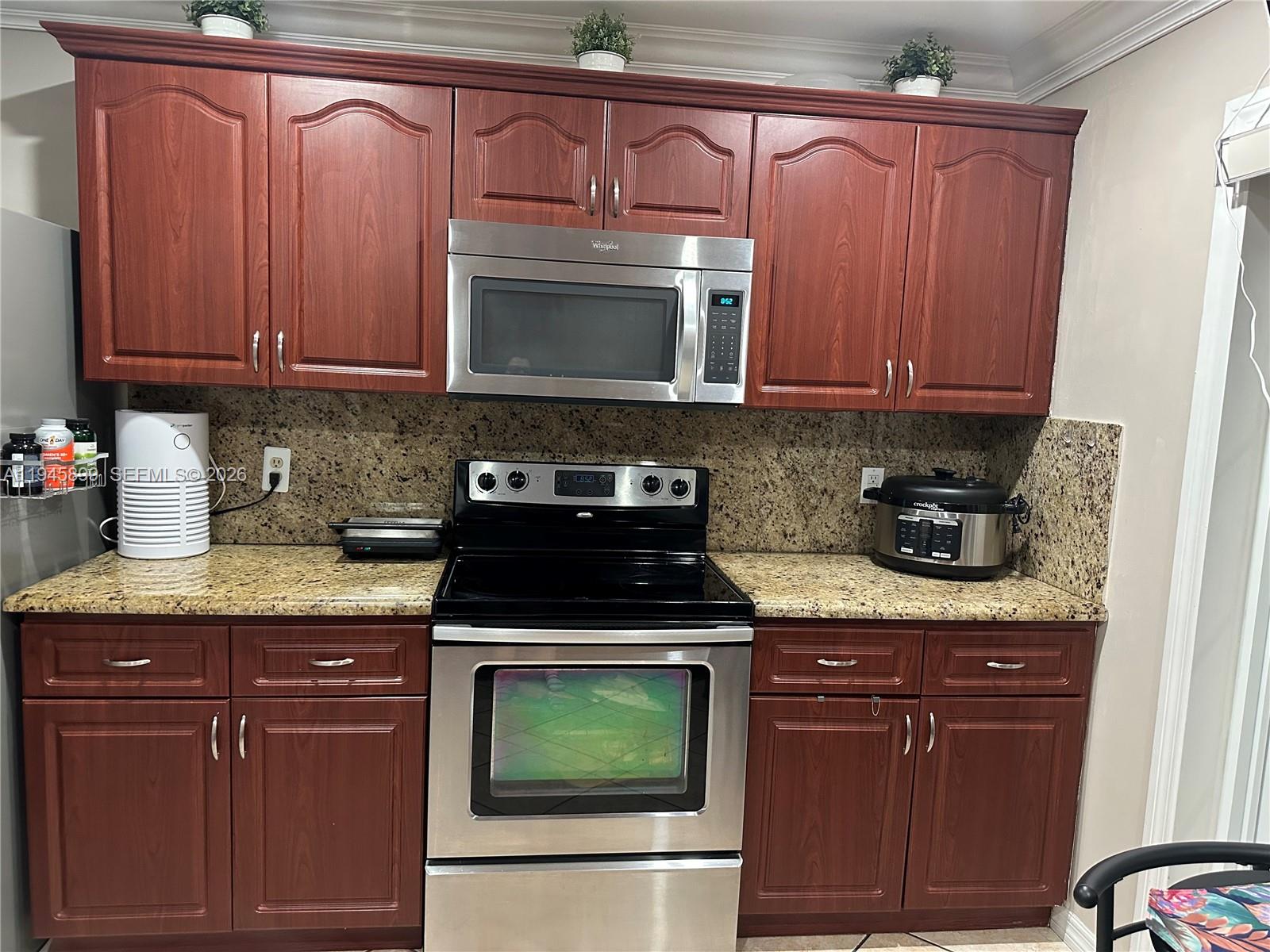 13220 Southwest 58th Terrace, Unit 166 Miami, FL 33183 - Photo 4 of 4 a kitchen with granite countertop wooden cabinets and a stove top oven