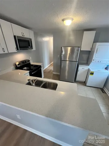 a kitchen with stainless steel appliances a refrigerator a sink a stove a microwave a counter top space and cabinets