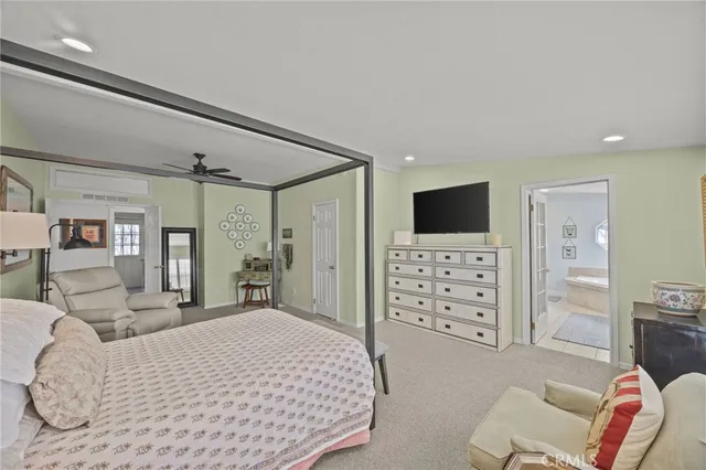 a spacious bedroom with a bed a couch and a flat screen tv