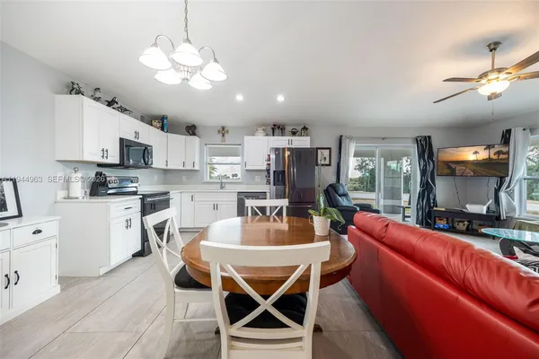 a view of a dining room with furniture a kitchen and chandelier