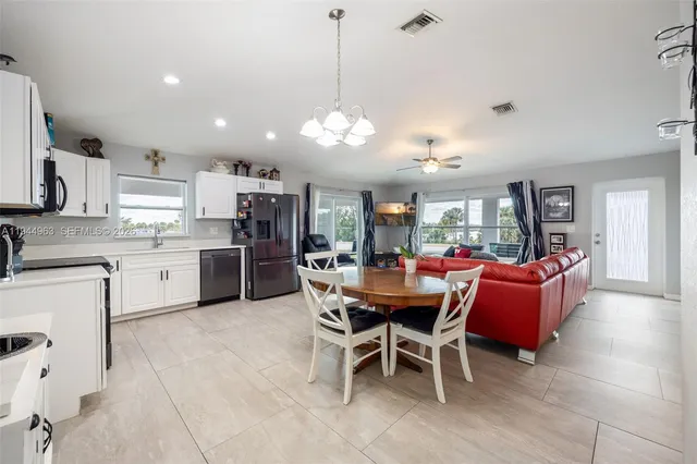 a dining room with kitchen island stainless steel appliances furniture a chandelier and kitchen view
