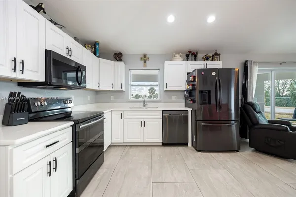 a kitchen with stainless steel appliances granite countertop a refrigerator stove a sink and a oven with wooden floor