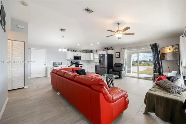 a living room with furniture kitchen view and a large window